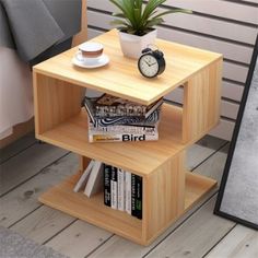 a small wooden shelf with books and a plant on top, next to a clock