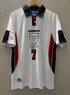 the jersey worn by umbro's team is displayed on a hanger in front of a wall