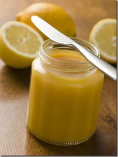 a jar filled with liquid sitting on top of a wooden table next to lemons