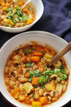 two bowls filled with soup on top of a blue table cloth next to a wooden spoon