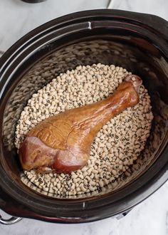 a large piece of meat in a slow cooker filled with sesame seeds and other ingredients