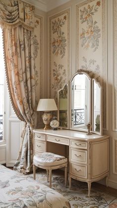 a dressing table with a mirror, stool and lamp in front of a floral wallpapered bedroom