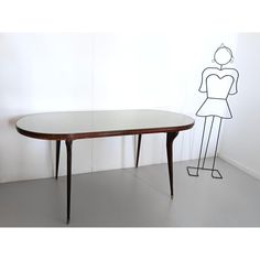 a wooden table with a drawing of a woman on the wall behind it and a person standing next to it