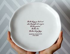 two hands holding a white plate with a poem on it