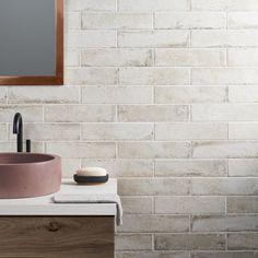 a bathroom sink sitting next to a mirror on top of a wooden cabinet under a mirror