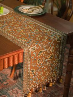 a wooden table topped with a green vase filled with flowers and plates on top of it