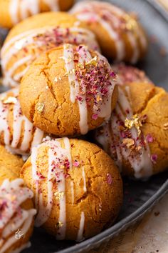 several cookies with white icing and sprinkles in a plate on a table