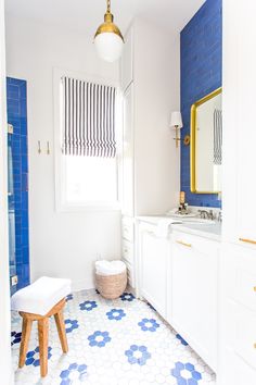 a bathroom with blue and white tiles on the floor, sink, mirror and stool