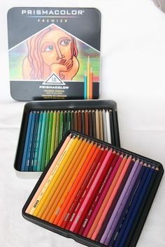 there are many colored pencils in the box next to each other on the bed