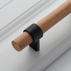 a wooden handle on the side of a white door with a black rubber band around it