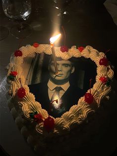 a heart shaped cake with a candle in the shape of a man's face