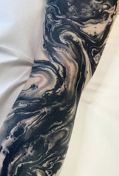 a man's arm covered in black and white marbled ink, with his hand on top of the arm