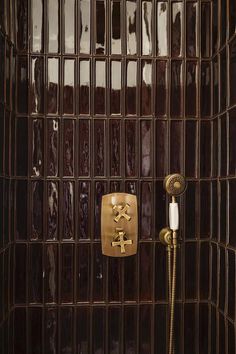 a brown tiled shower with a gold faucet and hand shower head in the corner