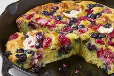 a close up of a cake in a pan with berries on it and one slice missing