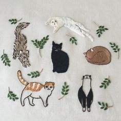 several cats and kittens are embroidered onto the white fabric with green leaves on it