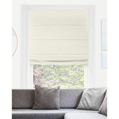 a living room with a couch and window covered in white roman blind shades on the windowsill