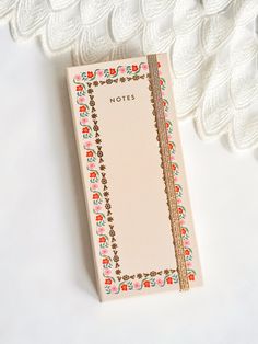 a notepad sitting on top of a white table next to a lace doily