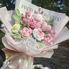 a person holding a bouquet of crocheted flowers in front of a sign that says pretty haps studio