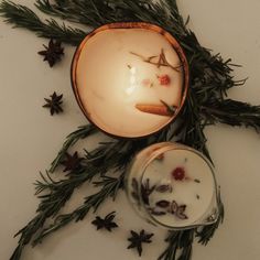 an arrangement of herbs and candles on a white surface with dried flowers in the center