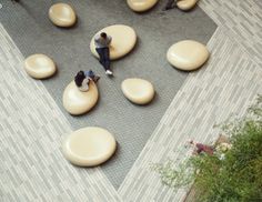 two people sitting on bean chairs in the middle of an open area with other people standing around