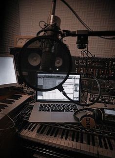 a laptop computer sitting on top of a desk next to a keyboard and headphones