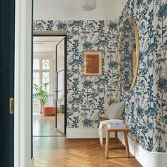 a room with blue and white wallpaper, wooden flooring and a mirror on the wall