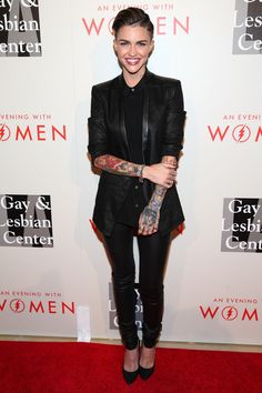 a woman with tattoos standing on a red carpet