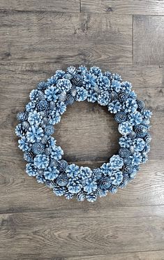 a wreath made out of pine cones sitting on top of a wooden floor