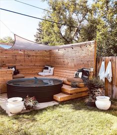 a hot tub sitting in the middle of a yard next to a wooden privacy fence