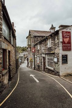 an empty street with stone buildings on both sides and a red sign hanging from the building