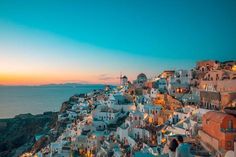 people are standing on the edge of a cliff overlooking the ocean at sunset or dawn