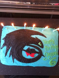 a birthday cake with lit candles on it and the image of a demon is shown