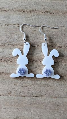 the earrings are made out of plastic and have ears shaped like rabbits with blue glitter on them