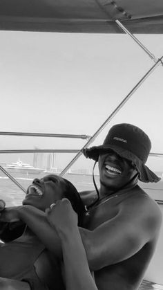 two people on a boat in the water smiling and hugging each other's shoulders