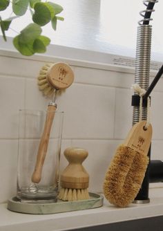 two wooden brushes are on the counter next to a glass and brush holder with a wood handle