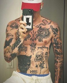 a man with tattoos taking a selfie in the mirror while holding his cell phone up to his face