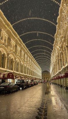 the inside of an indoor shopping mall with christmas lights hanging from the ceiling and cars parked on the street