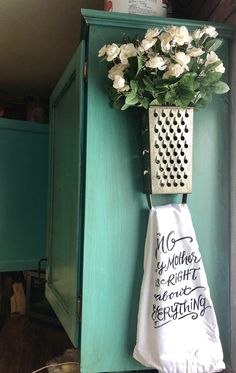 a teal cabinet with a white towel hanging from it's side and a bouquet of flowers on the door handle