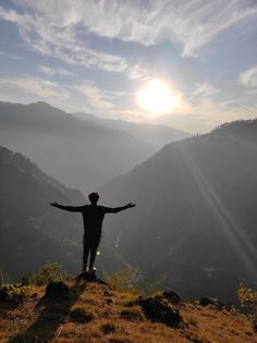 a man standing on top of a hill with his arms outstretched