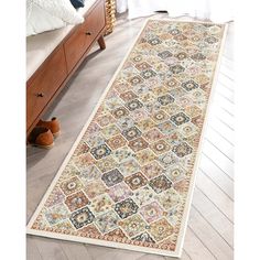 a large rug with many different colors and patterns on the floor next to a bed