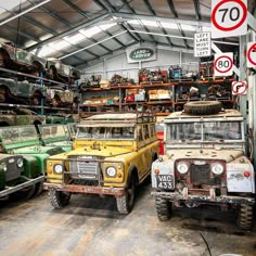 several old trucks and jeeps are parked in a garage