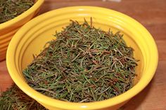 two yellow bowls filled with dried herbs on top of a wooden table