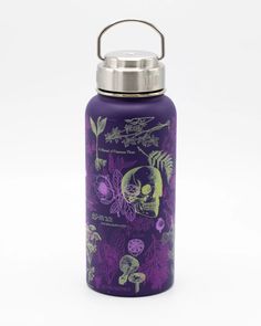 thermos bottle is decorated with skulls and leaves on purple, while it holds a stainless steel carafe