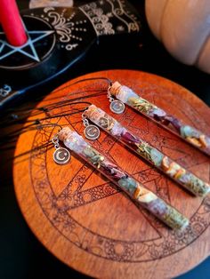 four pens sitting on top of a wooden board next to a candle and some other items