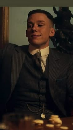 a man wearing a suit and tie sitting in front of a wall with coins on it