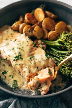 a bowl filled with chicken, potatoes and broccoli on top of a table