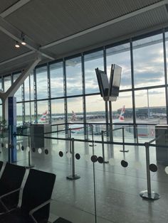 an airport terminal with lots of windows looking out onto the tarmac and planes in the distance