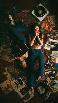 two people laying on the floor surrounded by records, cds and other things that are scattered around them