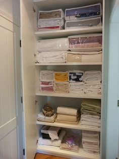 the closet is full of folded and unpacked items, including linens on shelves