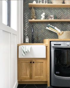 a washer and dryer in a small room with shelves on the wall behind them